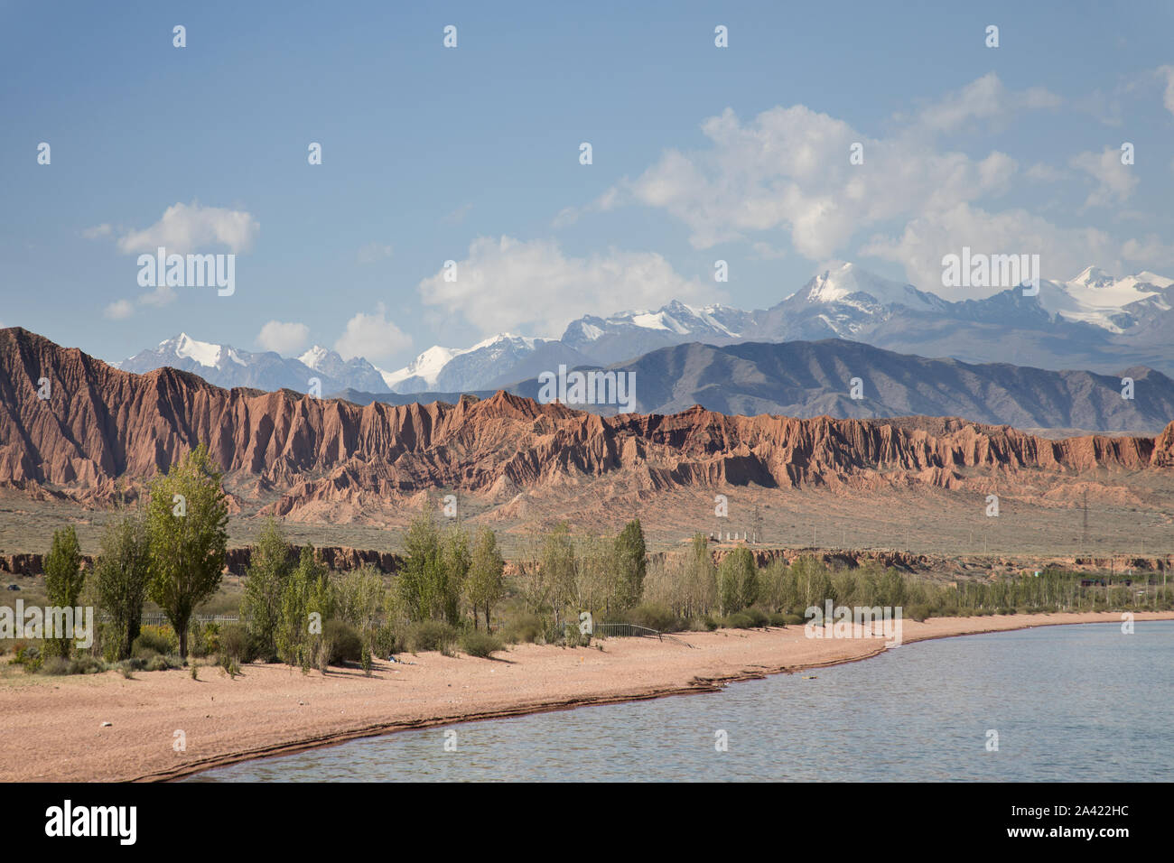 Issikul beach on the shores of lake issyk-kul with snow capped mountains in the ...