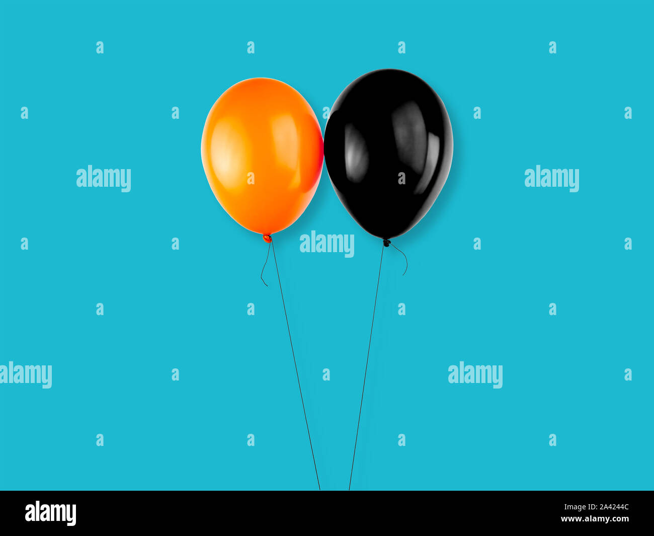 Orange and black colored balloons on light blue background. Halloween elements, text and copy space. Stock Photo