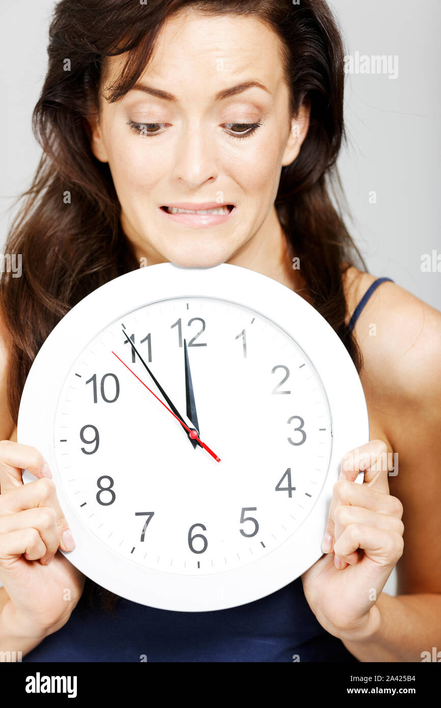 Young woman holding clock face expressing anticipation Stock Photo Alamy