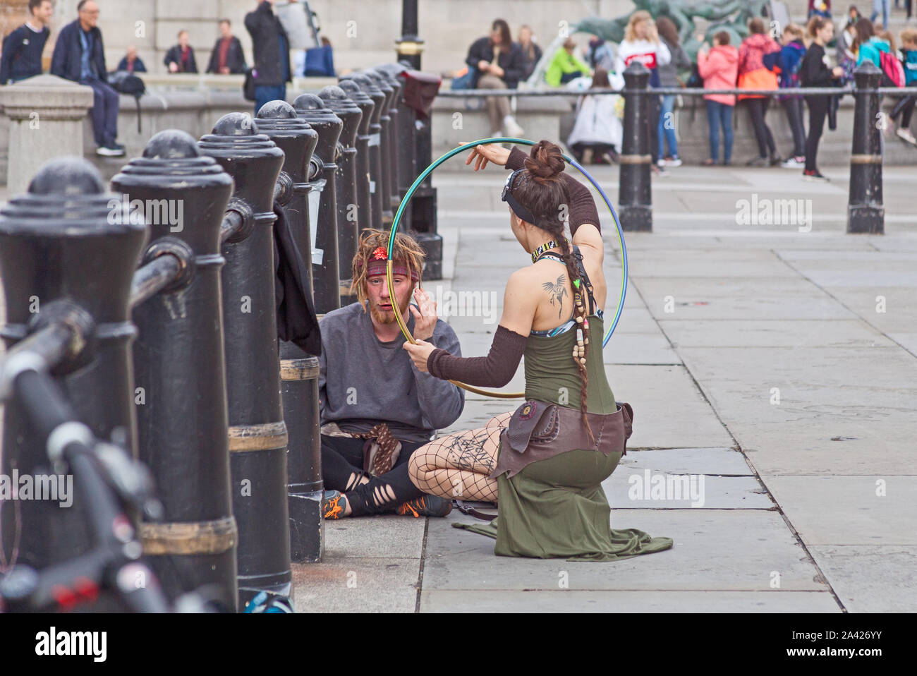 The first day of Extinction Rebellion's occupation of Trafalgar Square.  A demonstrator using her hula hoop to gain her sleepy friend's attention. Stock Photo