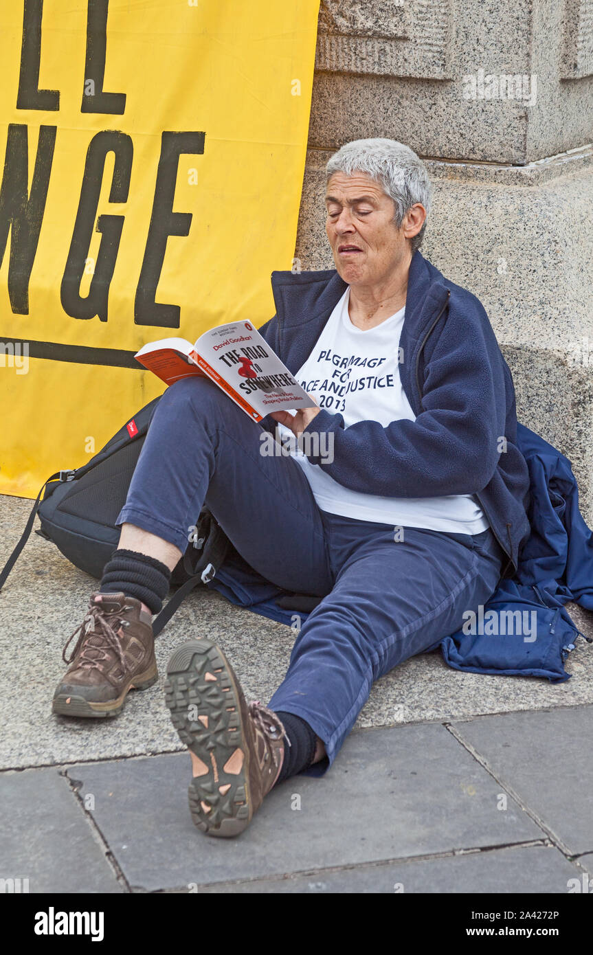 October 8th, 2019. The first day of Extinction Rebellion's occupation of Trafalgar Square.   Whiling away the time with suitable reading matter. Stock Photo