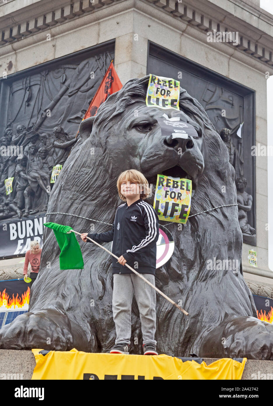 October 8th, 2019. The first day of Extinction Rebellion's occupation of Trafalgar Square.  A young demonstrator on one of the lion plinths. Stock Photo