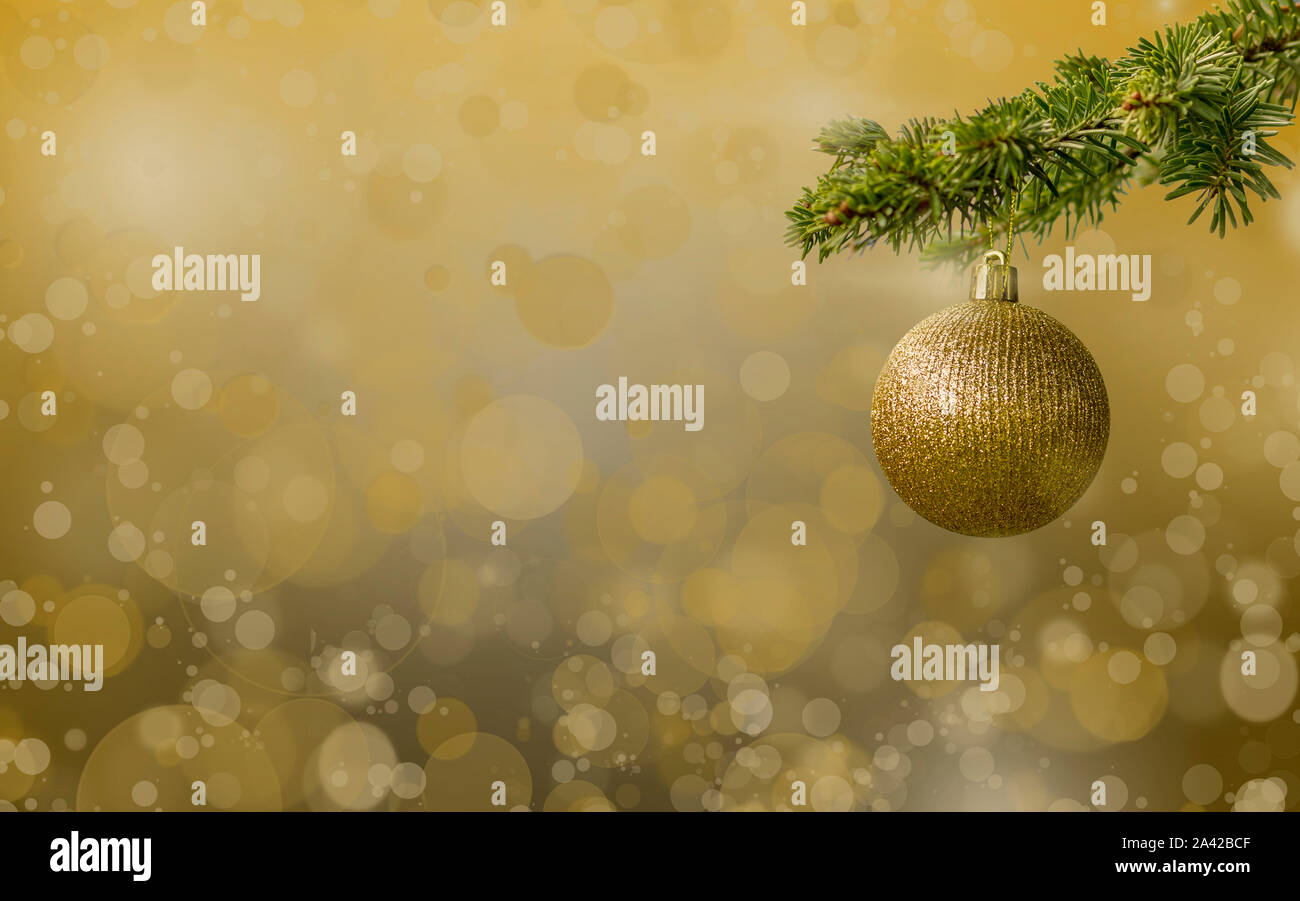 Fir tree branch with a golden glitter ball on white background. Bokeh effects. Christmastime. Christmas postcard. Stock Photo