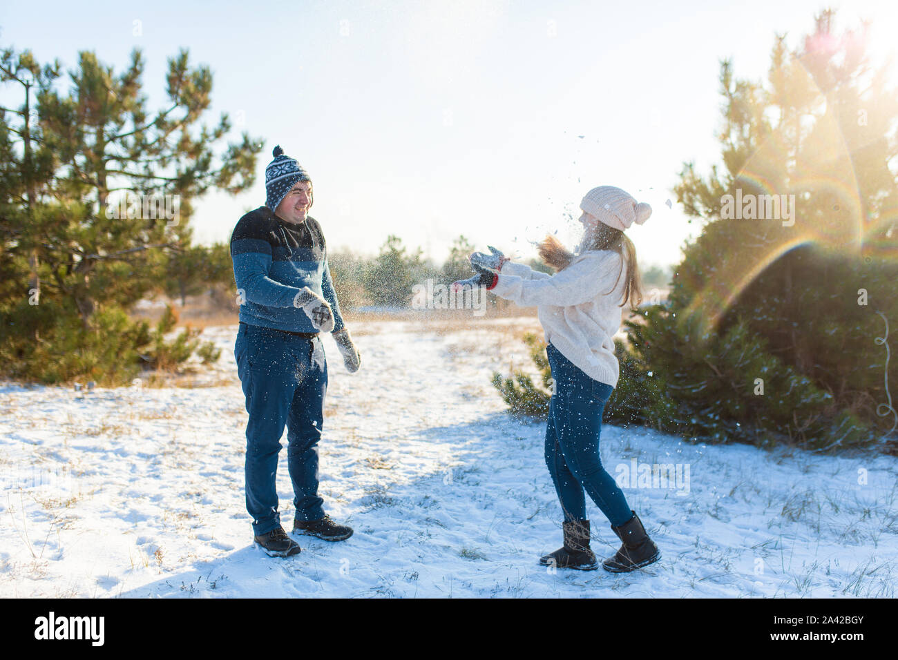 Loving couple play snowballs in winter in the forest. Throw each other ...