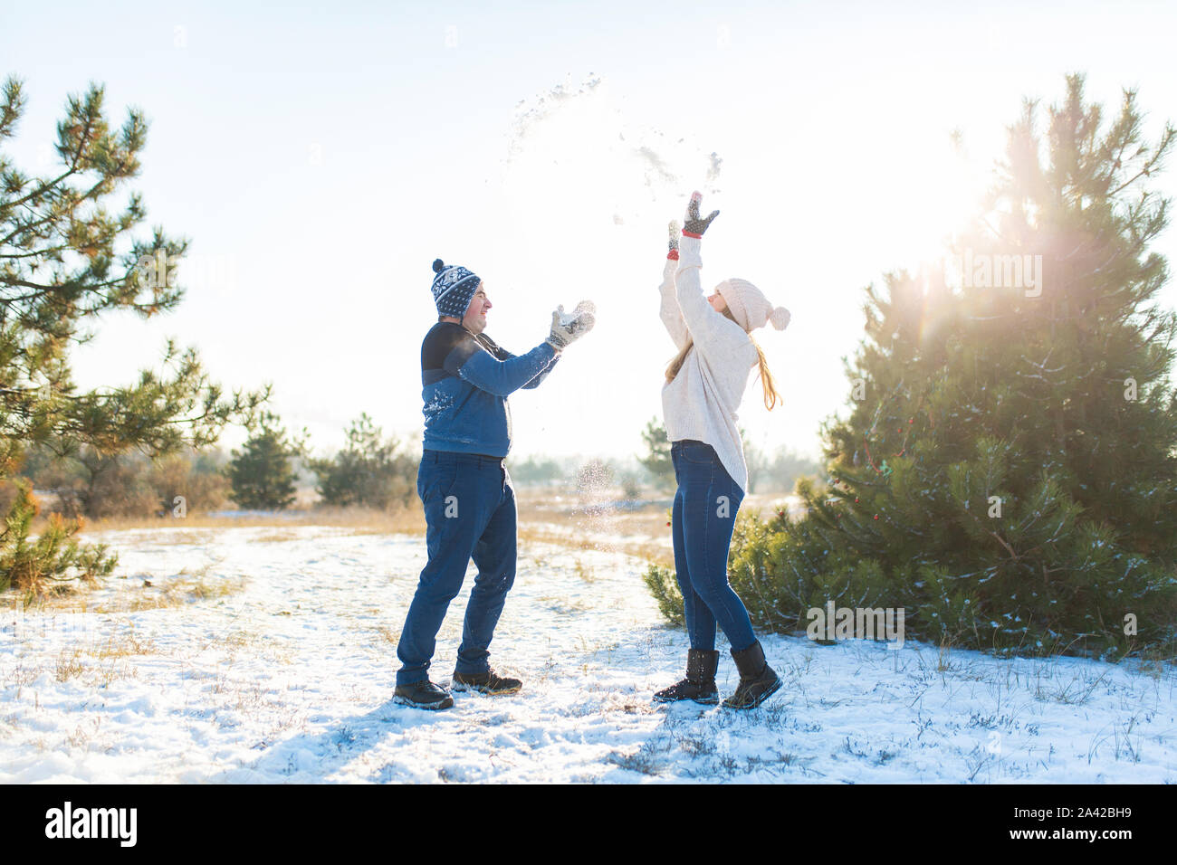 Loving couple play snowballs in winter in the forest. Throw each other ...