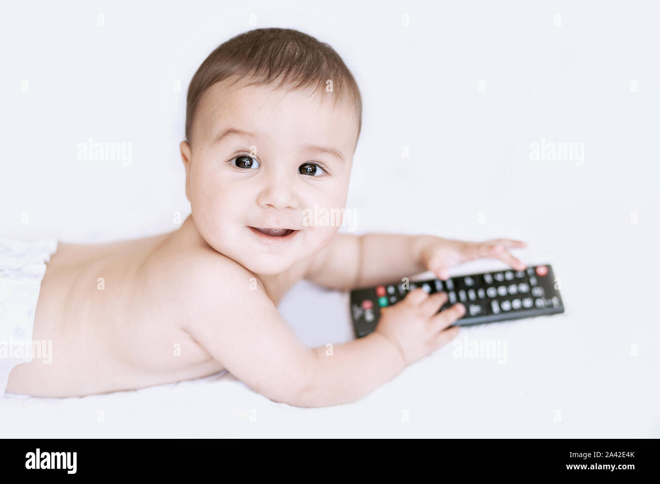 6 months old smiling baby boy grabbing the TV remote control from the