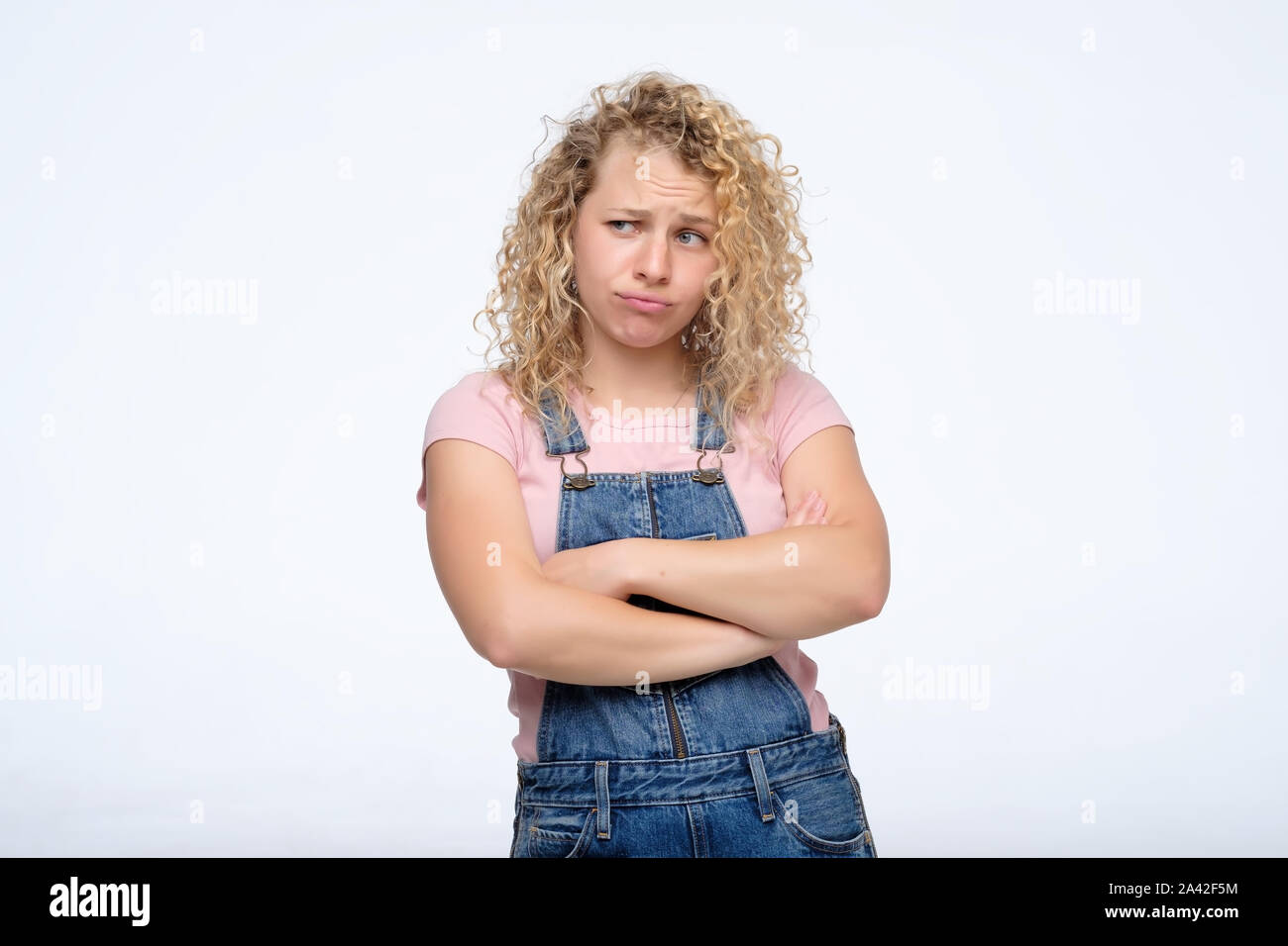 Blonde woman standing with arms folded and looking away Stock Photo