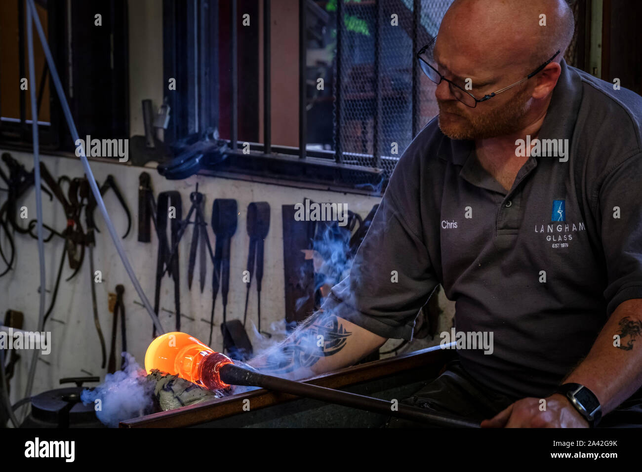 A craftsman forming a vase out of molten glass. Stock Photo