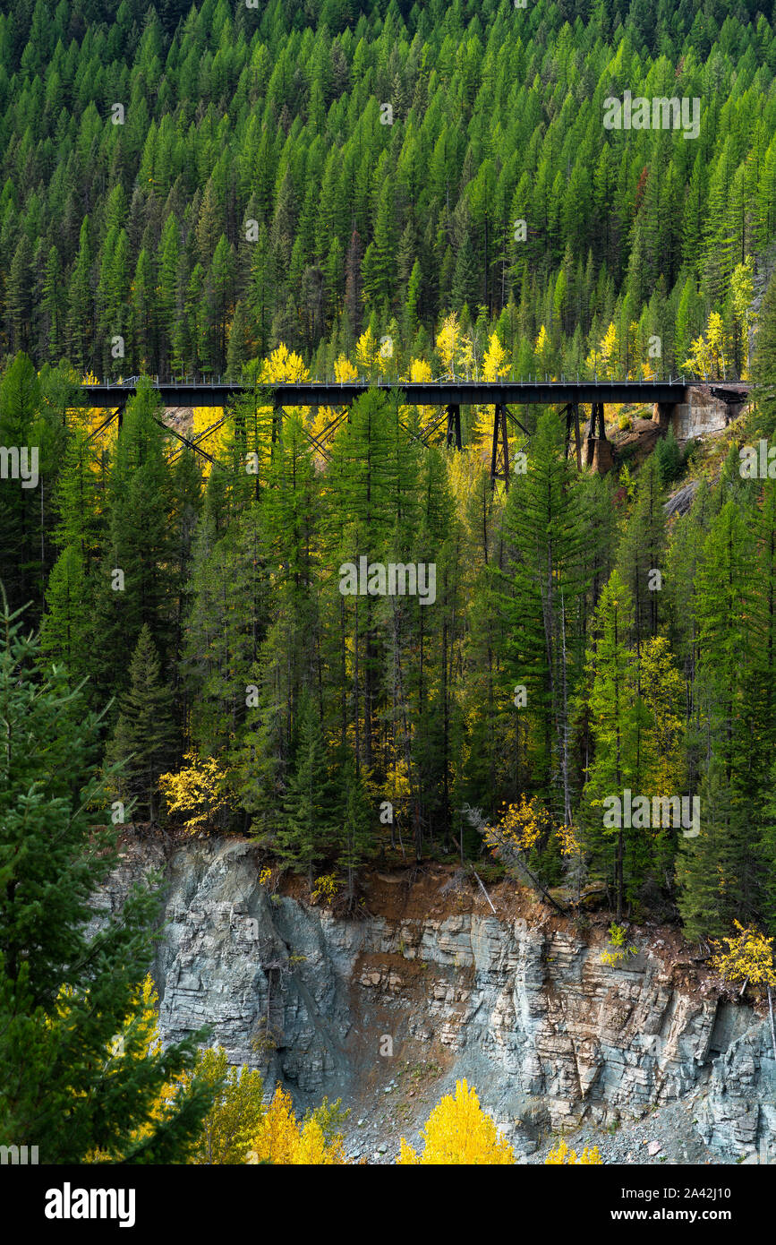 The Railroad at Glacier National Park between the Fall Season colored trees and the ledge below, Montana. Stock Photo