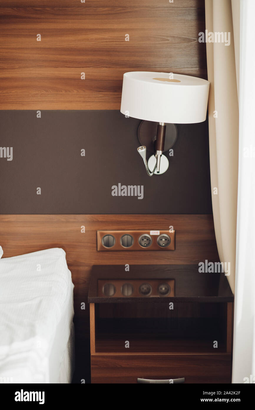 Modern night lamp and bedside table with sockets near bed surrounded by  luxury hotel interior background. Fashionable beautiful day light floor  lamps Stock Photo - Alamy