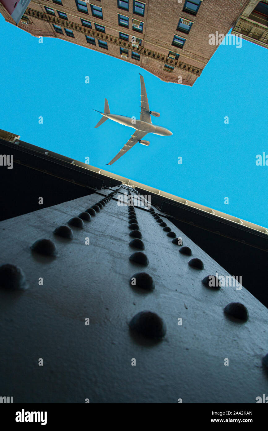 Looking up view of cast iron buildings in New York City with an airplane over a blue sky. Stock Photo