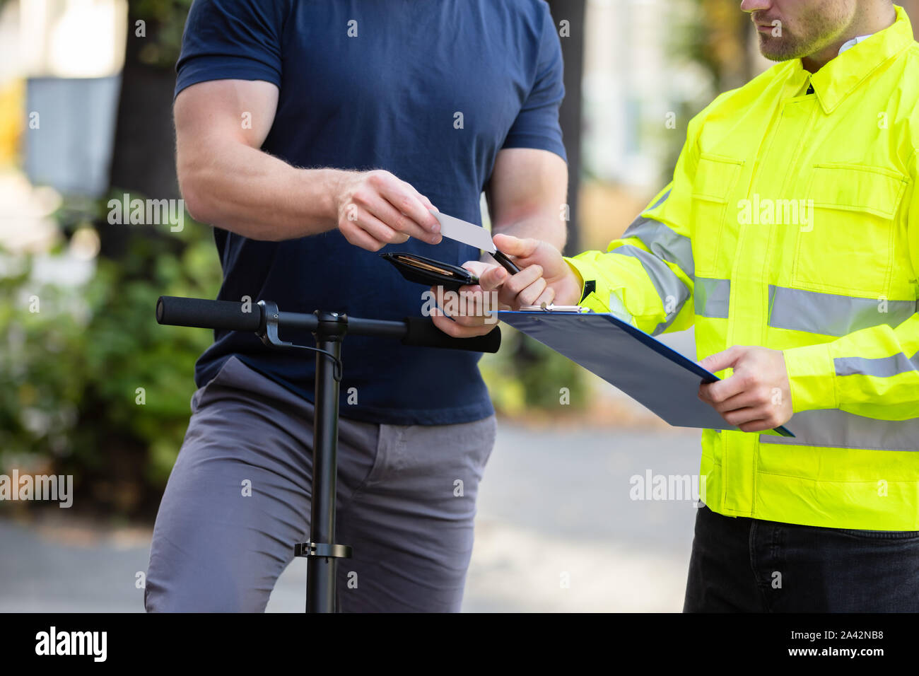 Mid Section Of A Man On Electric Scooter Showing Drivers License To The