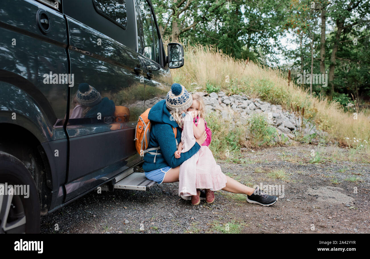 mother and daughter hugging outside a camper van whilst camping Stock Photo