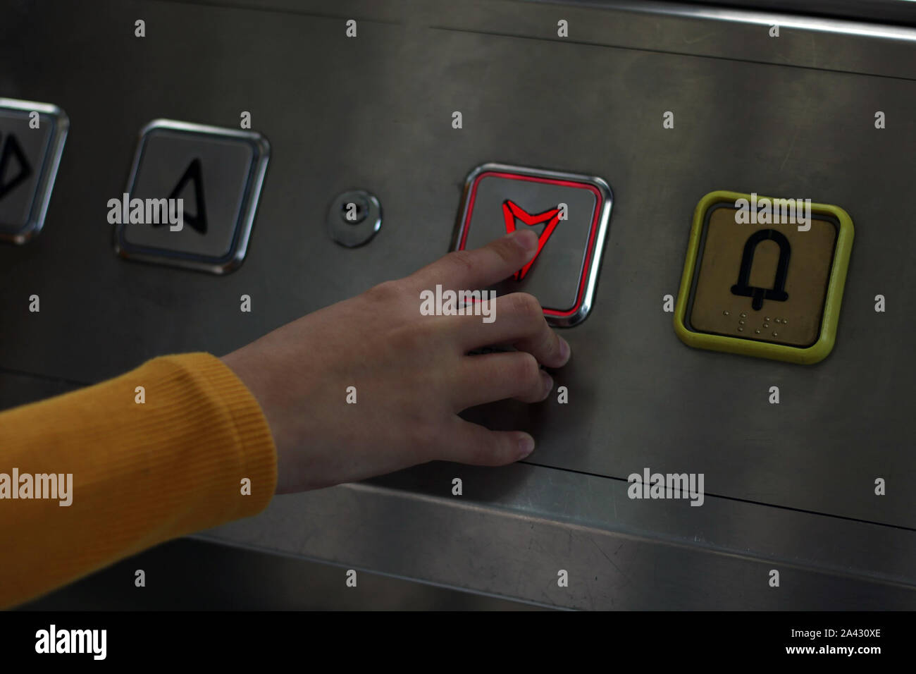 Girl dressed in yellow pressing the elevator button. Elevator to access