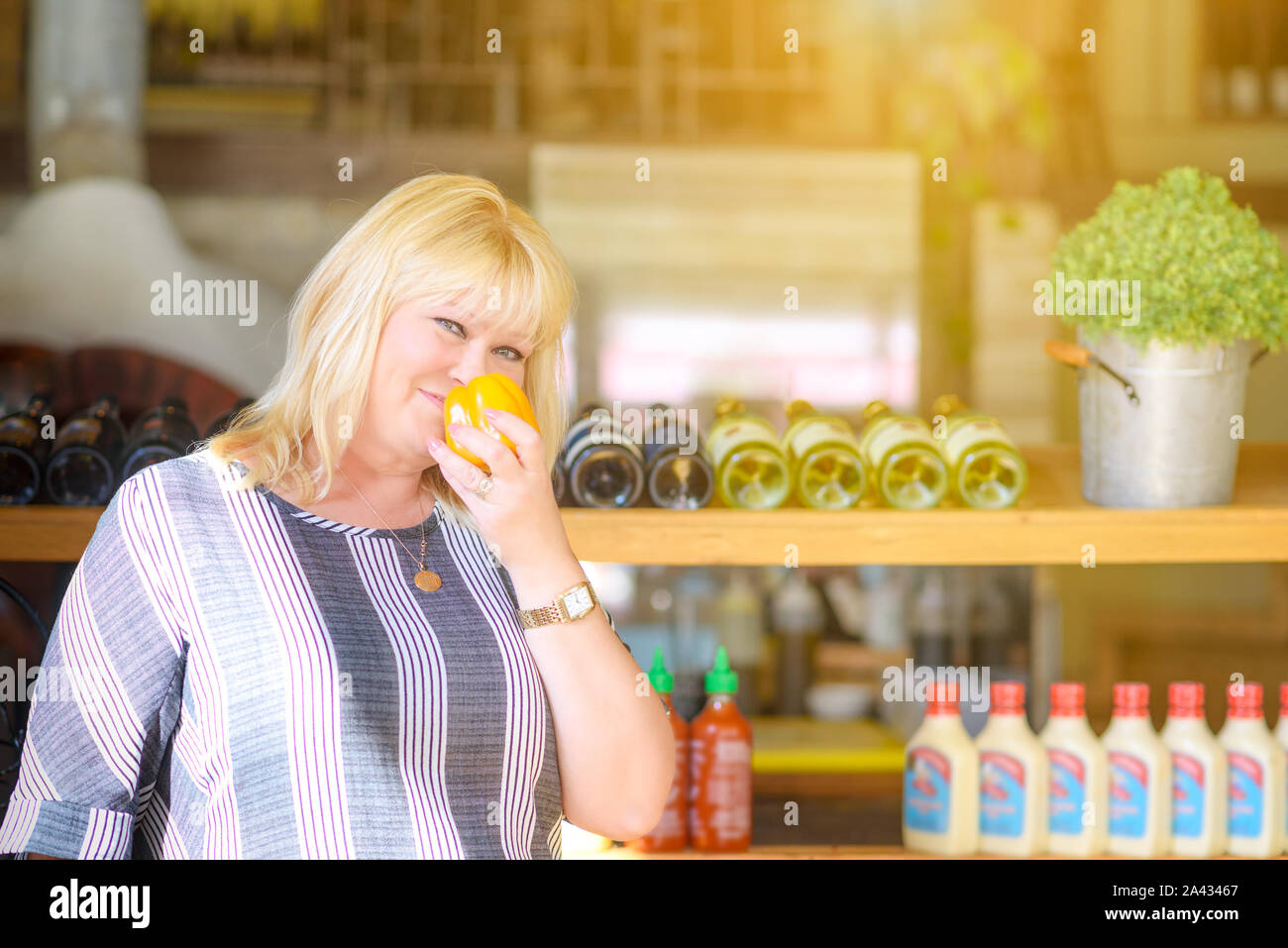 Portrait of a happy senior merchant standing with sweet pepper in store