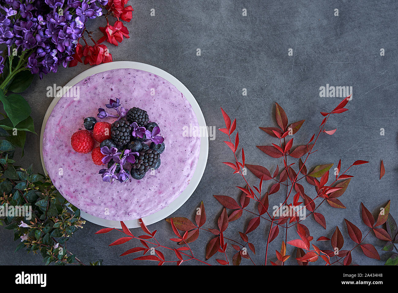 Ice cream cheesecake and berries on a background in green tones. Accompanied with a basket of blueberries, blackberries and raspberries. Stock Photo