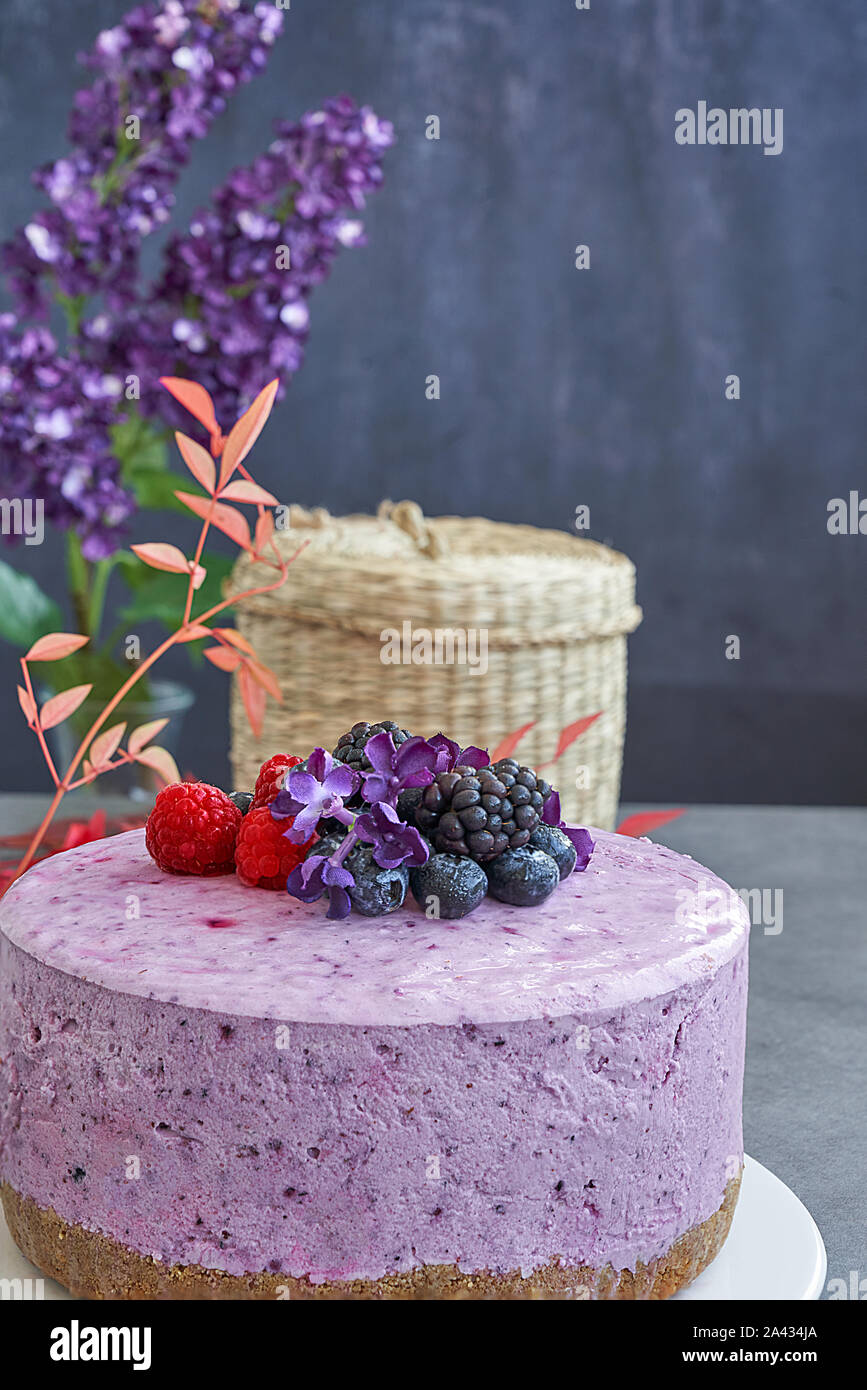 Ice cream cheesecake and berries on a background in green tones. Accompanied with a basket of blueberries, blackberries and raspberries. Stock Photo