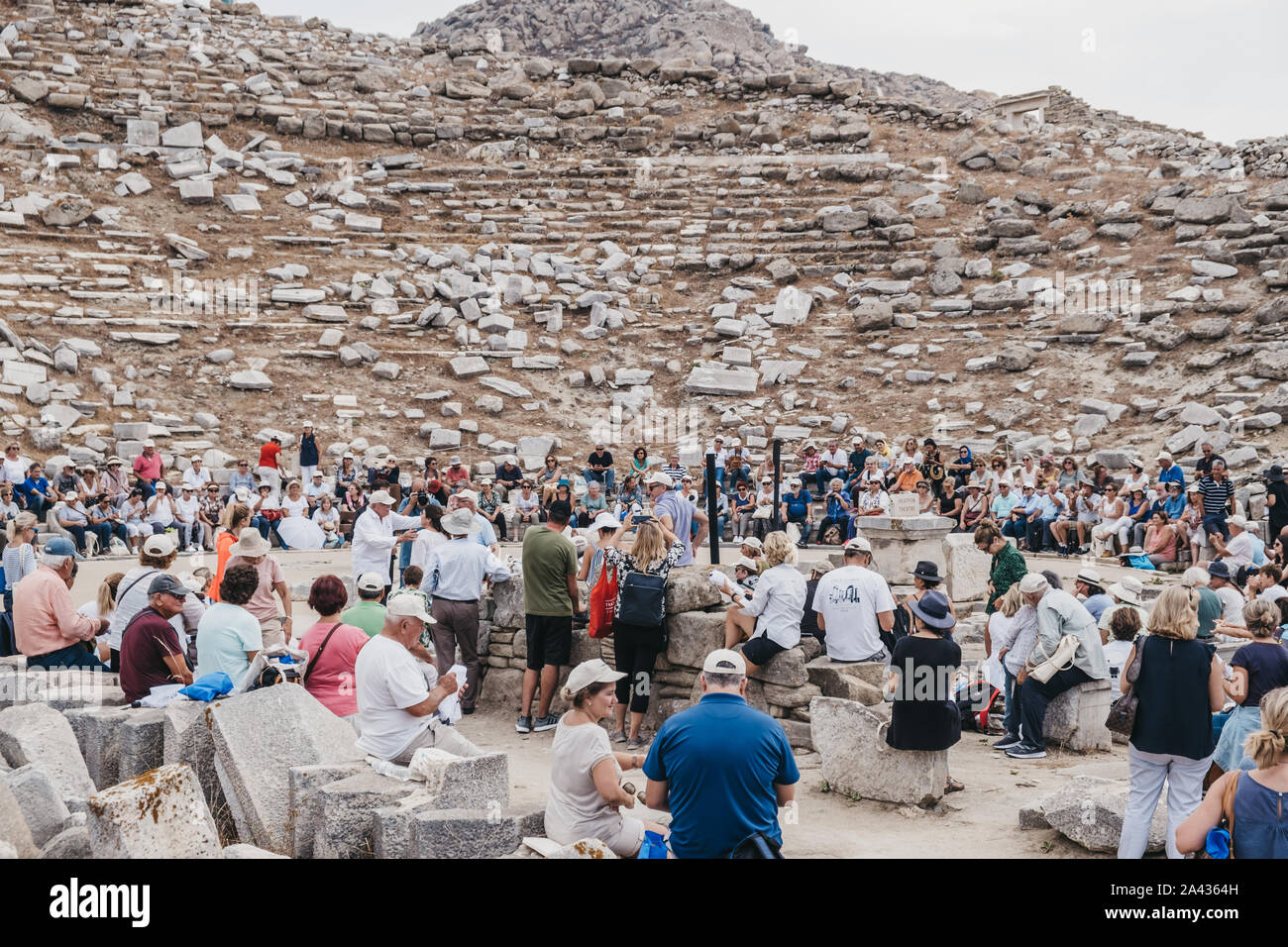 Delos, Greece - September 20, 2019: Large number of tourists watching performance at the ancient theatre on the Greek island of Delos, an archaeologic Stock Photo