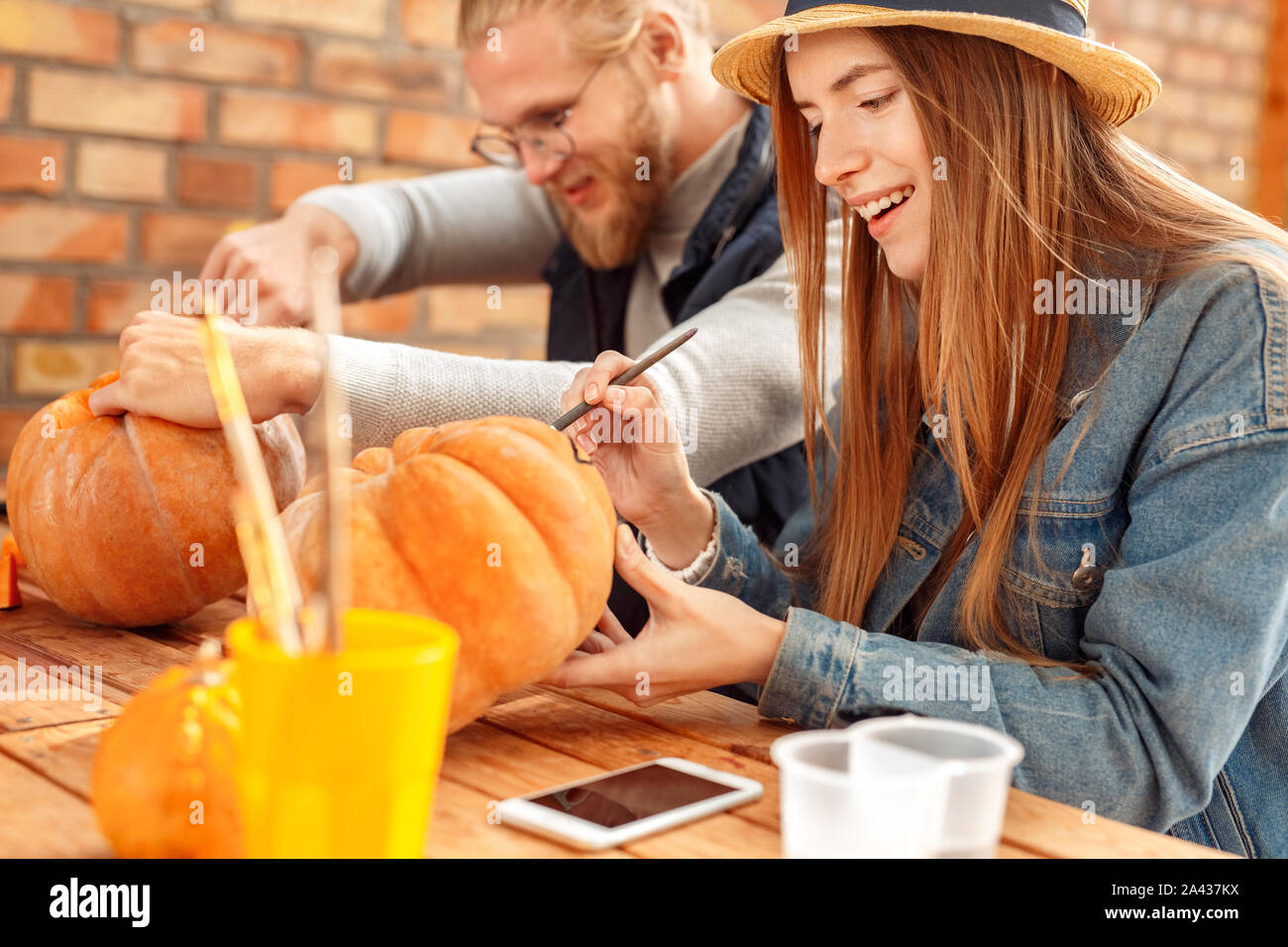 Young adult woman and man decorating ripe pumpkin for halloween Stock Photo