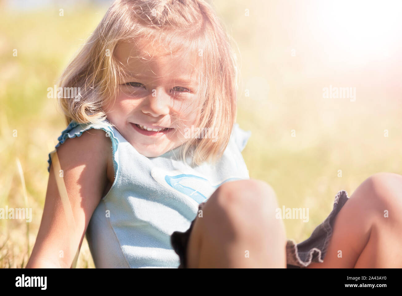 Happy smiling girl sitting in grass Stock Photo - Alamy