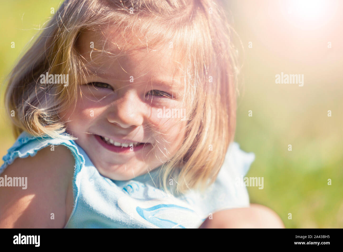 Happy smiling girl sitting in grass Stock Photo - Alamy