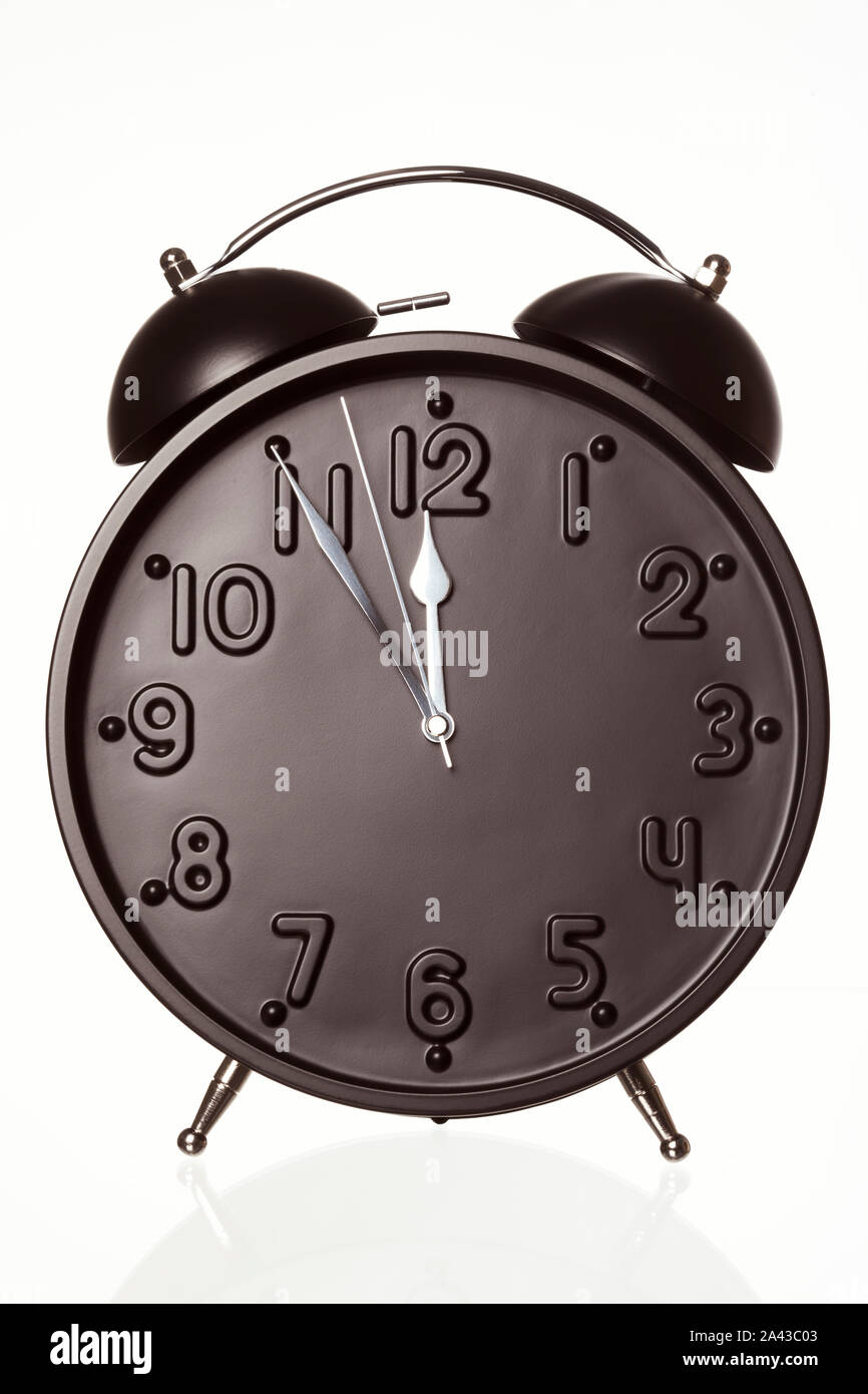 Alarm clock showing five minutes to twelve. Stock Photo