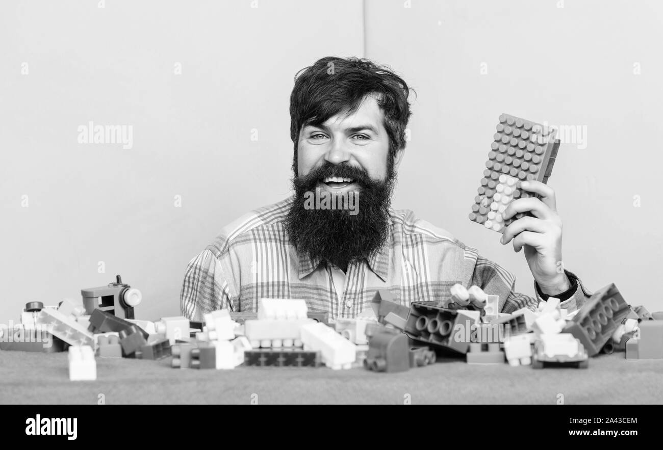 Just relax. happy father play game. bearded hipster man playing toy blocks. development. leisure time. building with colorful brick constructor. man nanny. nanny for kids. nurse in playroom. Stock Photo