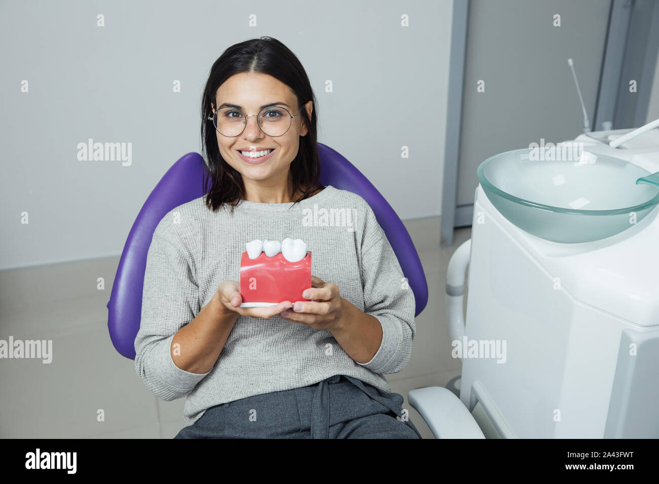Young female patient sitting on chair in dental office. Preparing for dental exam. Looking at camera Stock Photo