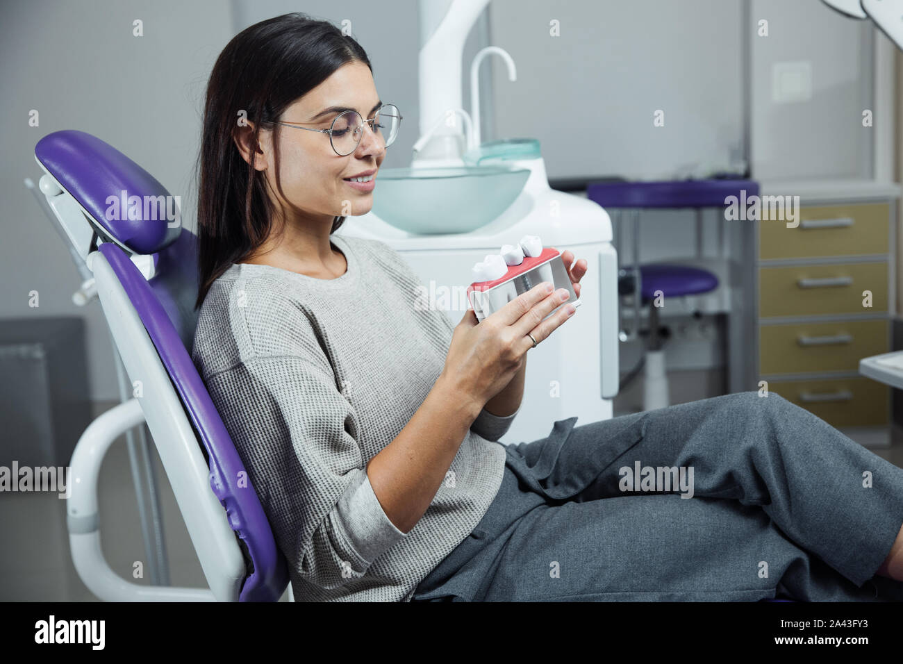 Young female patient sitting on chair in dental office. Preparing for dental exam. Looking at camera Stock Photo