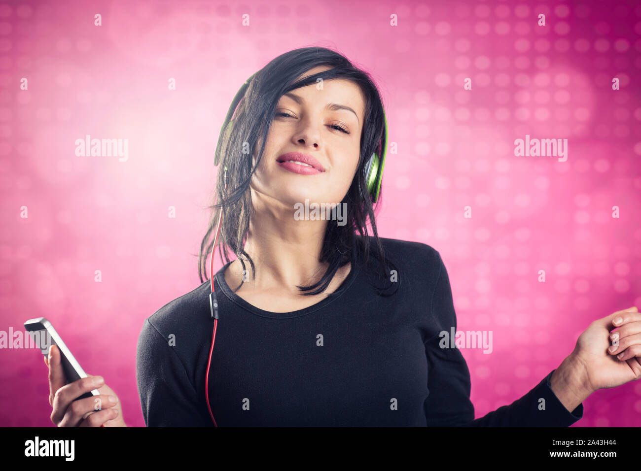 Smiling girl listening to music with earphones and dancing Stock Photo