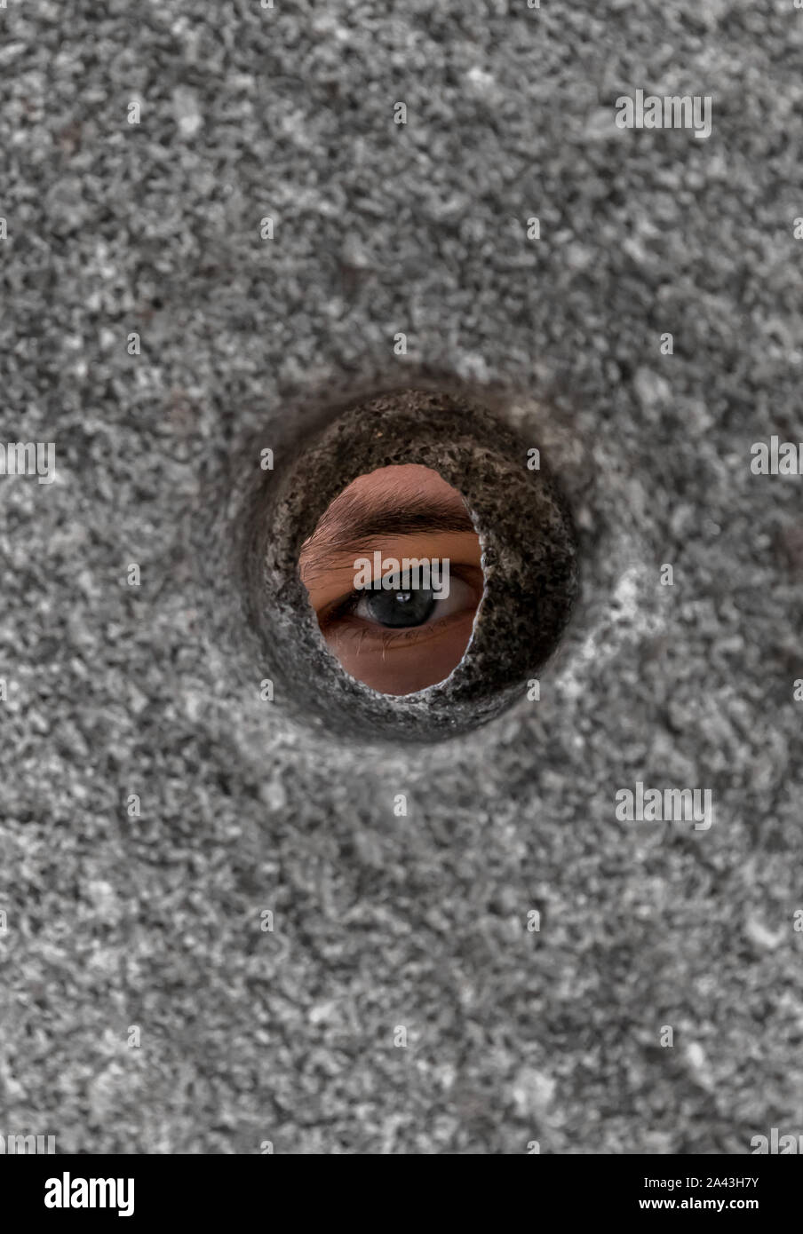 Open Eye Looking Through Round Hole In Stone Wall Stock Photo