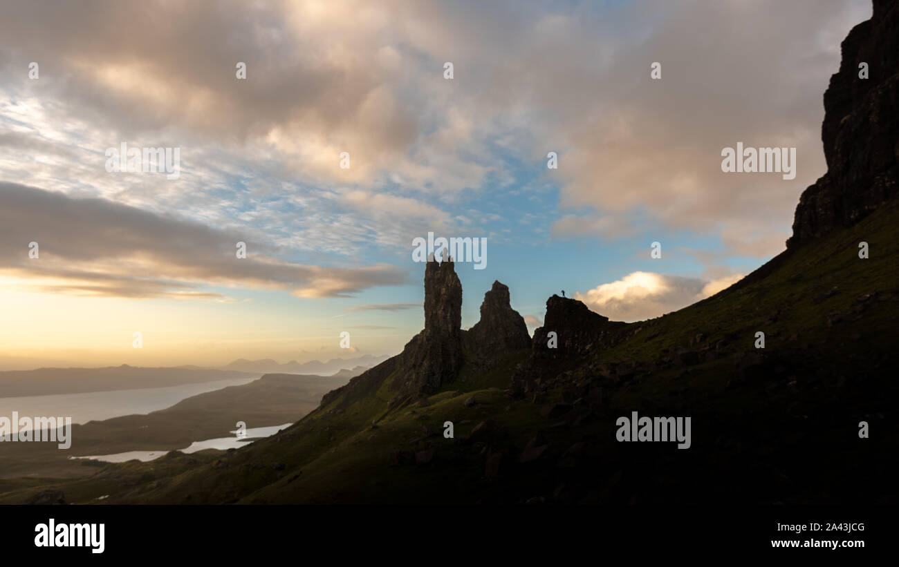 Old Man of Storr in silhouette at sunrise with person for scale Stock Photo