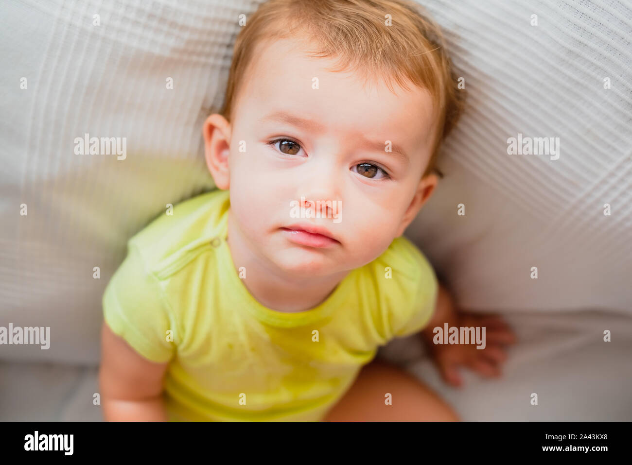Baby sitting looking towards the camera on him with intrigued gesture ...