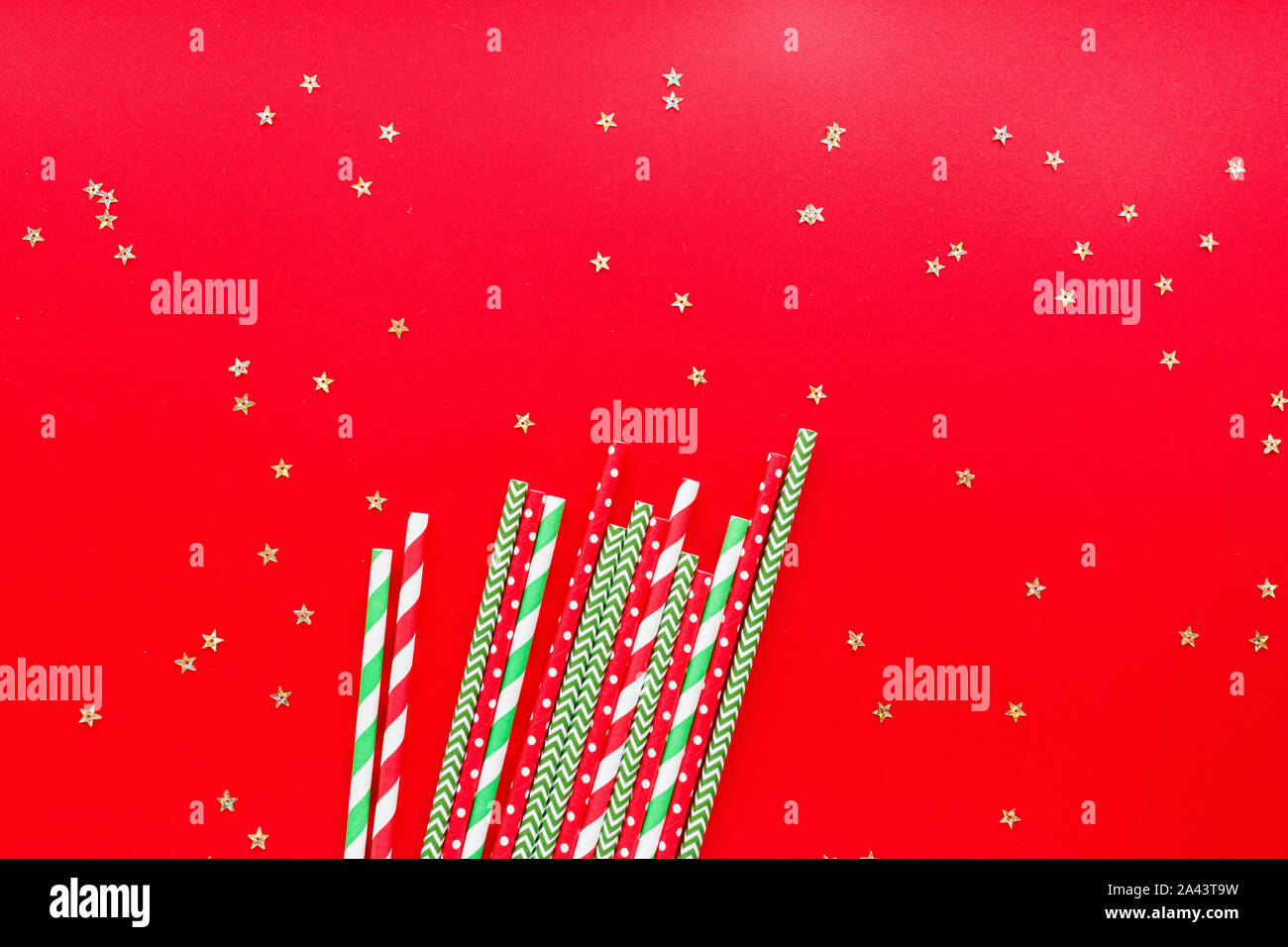 Striped drink straws of different colors on red background. New Year or Christmas pattern. Minimalism concept. Pop art style. Top view, Flat lay with Stock Photo