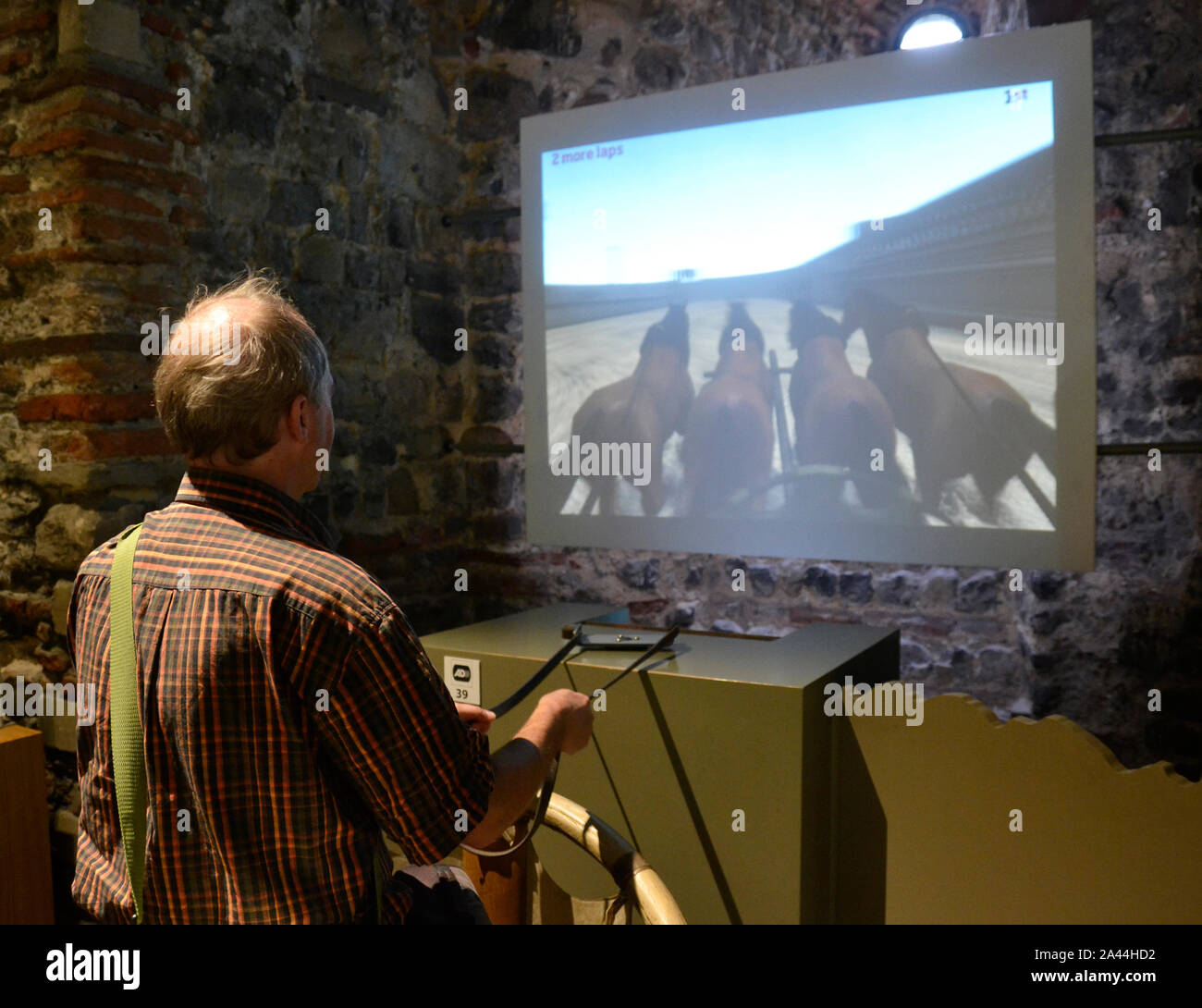 Man using the chariot racing game in the Roman Gallery, at Colchester Castle Museum, Colchester, Essex, UK Stock Photo