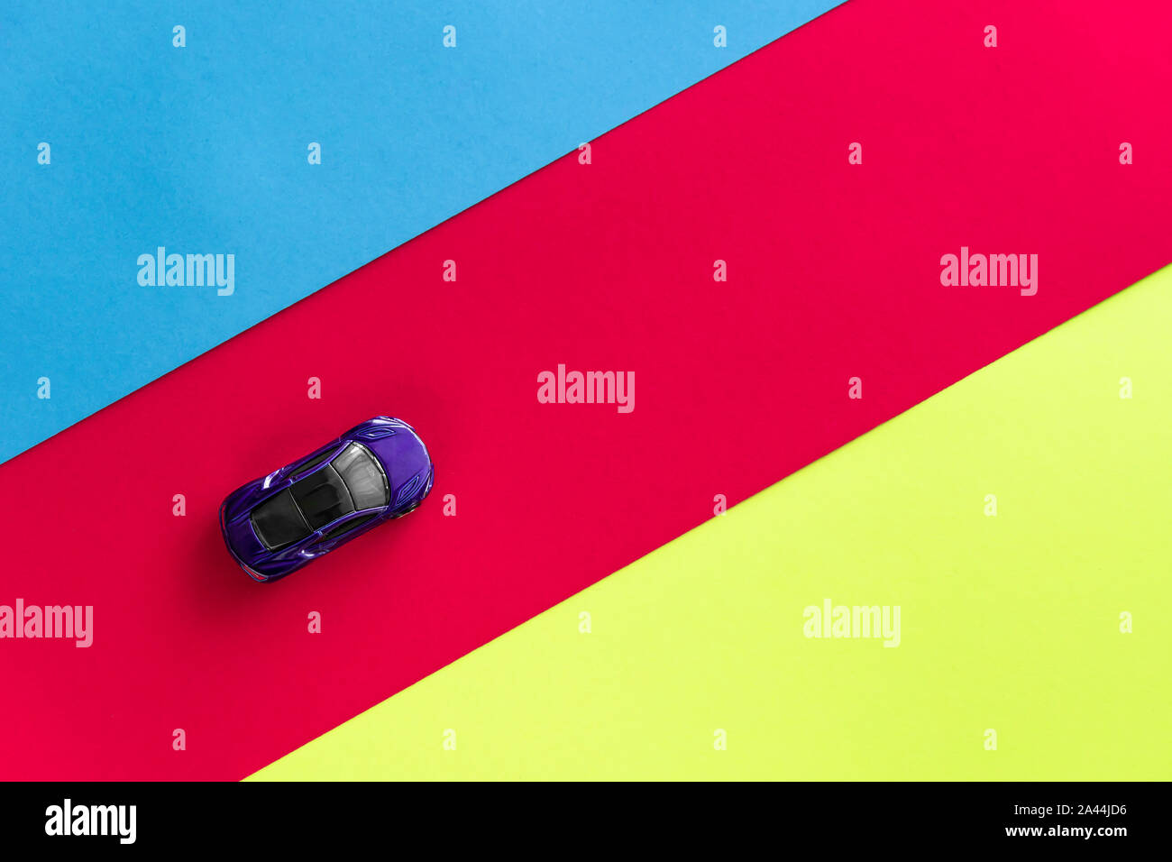 Kids toy car on trendy colorful background. Baby car top view on blue red yellow colored paper. Boys game. Travel and sport lifestyle. Business, transportation concept. Moscow, Russia - September 30, 2019 Stock Photo