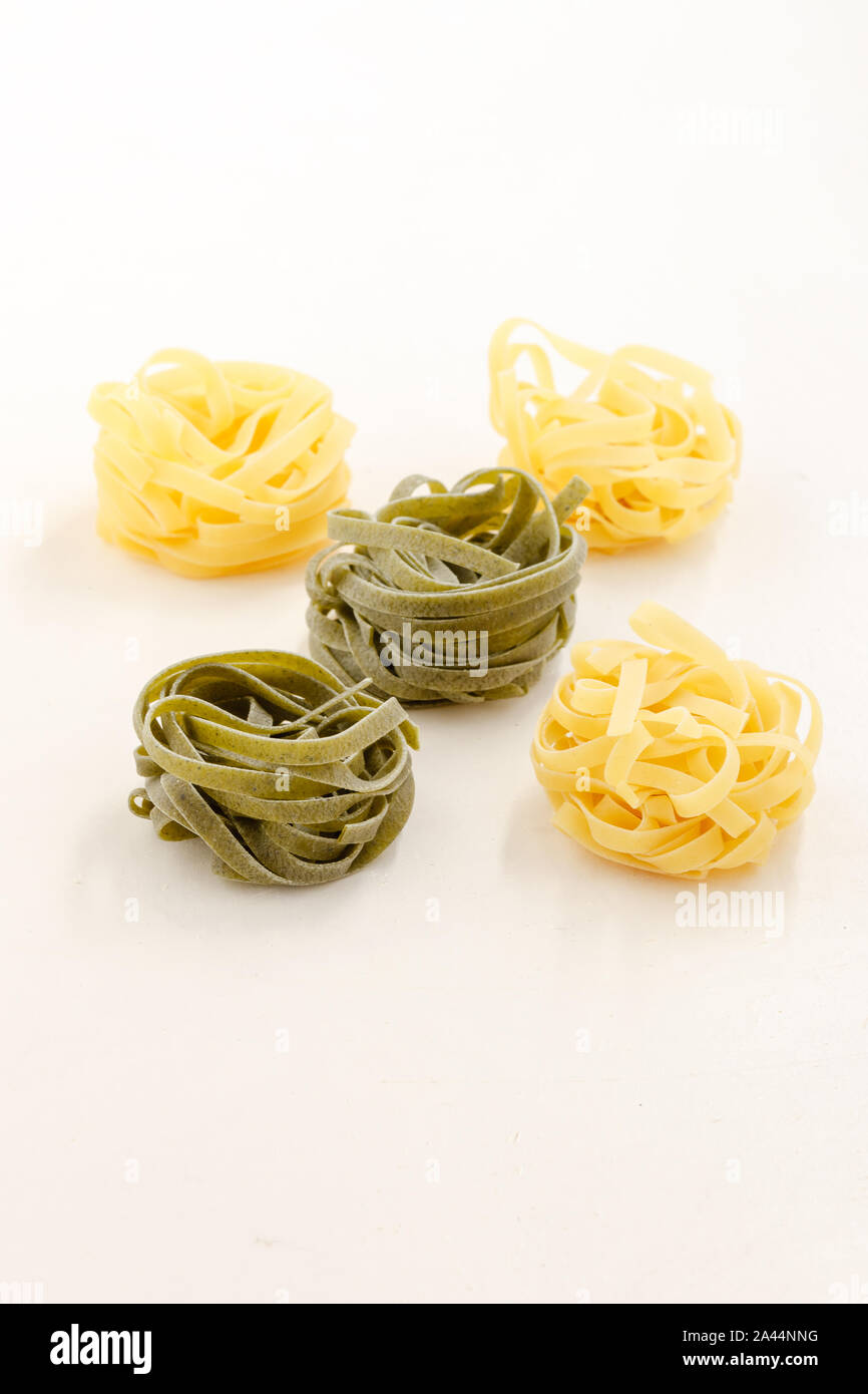 green and white pasta nests on structured white background Stock Photo