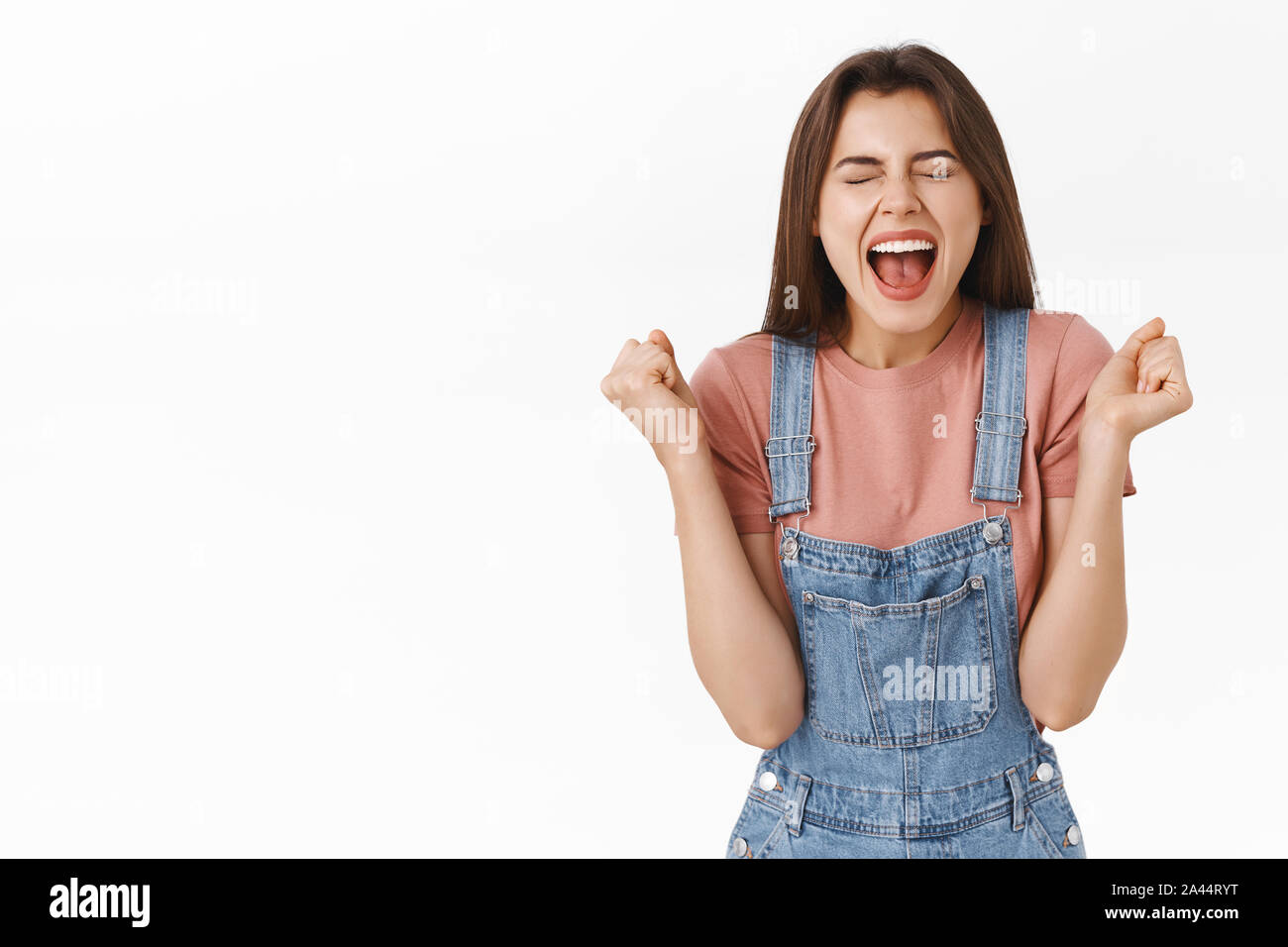 Relieved and happy attractive woman rejoicing, shouting yes joyfully clenching fists, achieve success, become champion or winner, close eyes triumphin Stock Photo