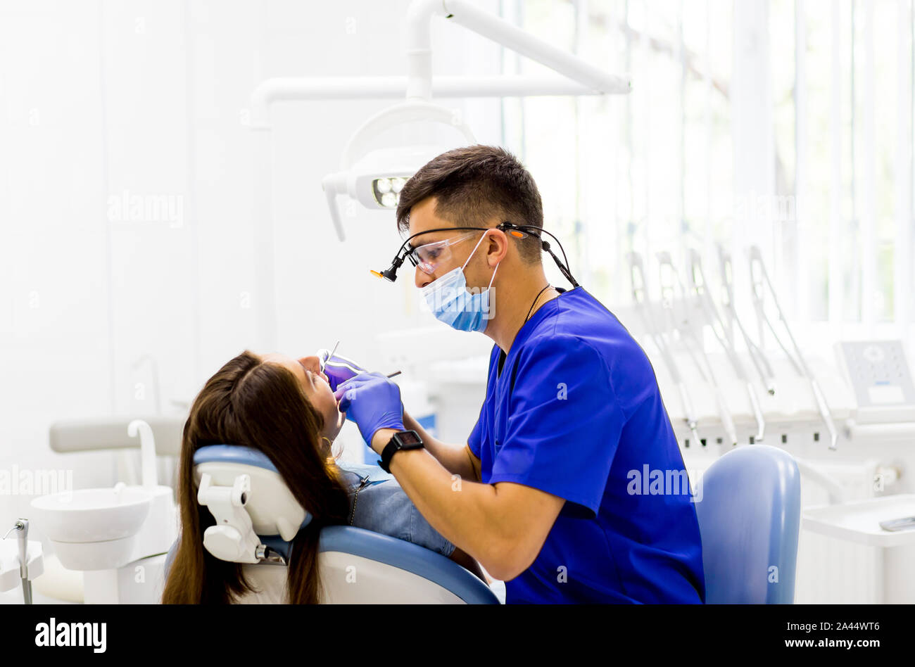 Dentist curing a female patient in dental clinic. Medical help and care of teeth. Stock Photo