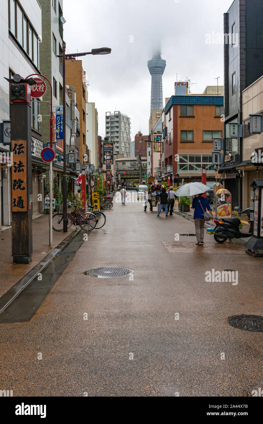 Tokyo, Japan - August 29, 2016: Japanese street in Asakusa district with famous Tokyo Skytree in the clouds. Tokyo Skytree is the tallest tower in the Stock Photo