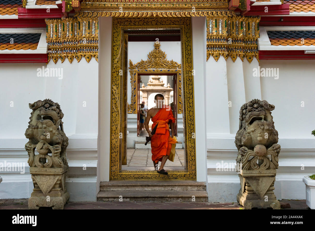 Bangkok, Thailand - Dec 24, 2015: Buddhist monk in orange robe go through doorway in Wat Pho temple inner yard Stock Photo