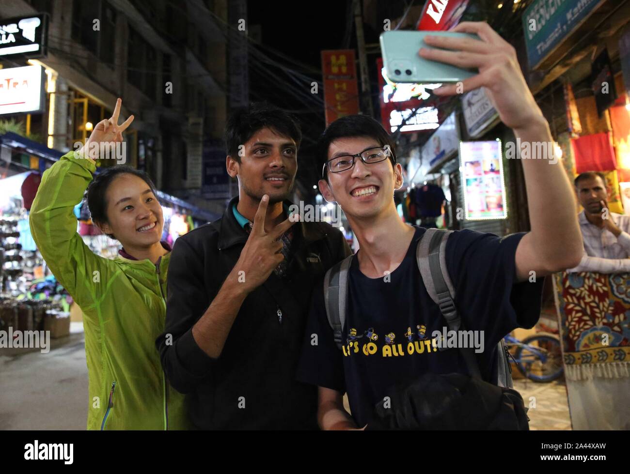 Kathmandu, Nepal. 7th Oct, 2019. Amit Baniya (C) poses for a photo with Chinese tourists in Kathmandu, Nepal, Oct. 7, 2019. Anyone hearing Amit Baniya's Mandarin would think the 23-year-old young man is Chinese. He knows almost all the buzzwords on the Chinese social media and is also an expert in using trending words and phrases to attract TikTok fans. TO GO WITH:Feature: Nepali TikTok celebrity invites all Chinese to visit his country Credit: Liu Tian/Xinhua/Alamy Live News Stock Photo