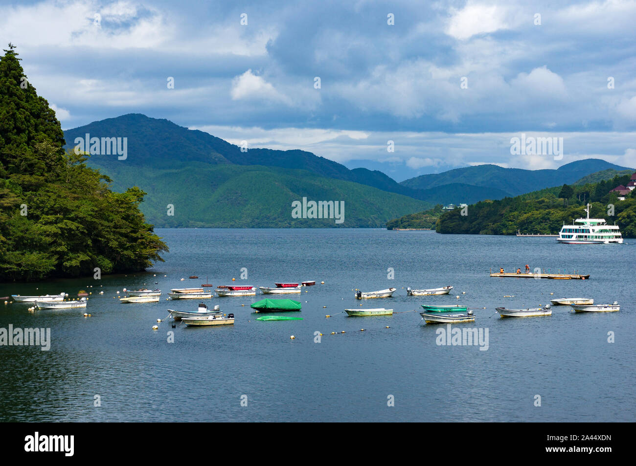 Hakone, Japan - September 3, 2016: Colorful fishing boats with mountains on the background on caldera lake Ashi. Ashi lake is volcano crater lake in M Stock Photo