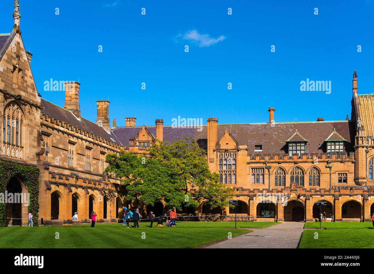 Sydney Uni inner yard with students in the distance enjoying break. University of Sydney courtyard against deep blue sky with white clouds, daytime ph Stock Photo