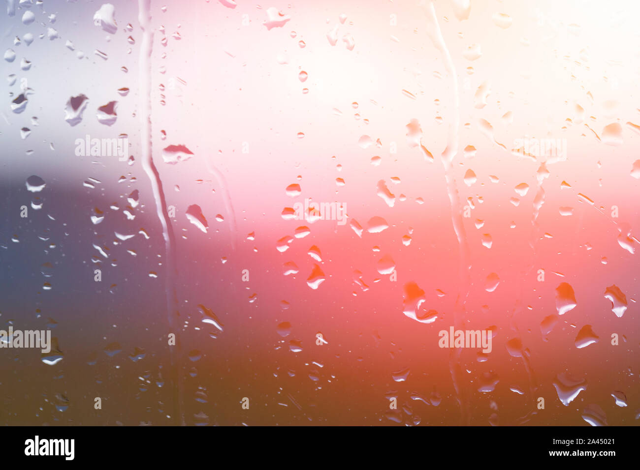 Drops of water on window glass after rain with dramatic blurred sunset on background. Idyllic tranquil nature wallpaper. Weather forecast. Stock Photo