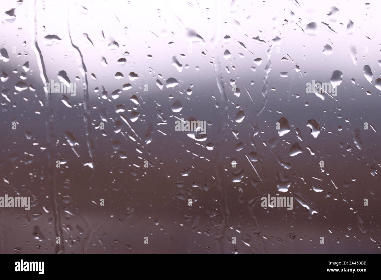 Drops of water on window glass after rain with dramatic blurred sunset on background. Idyllic tranquil nature wallpaper. Weather forecast. Stock Photo