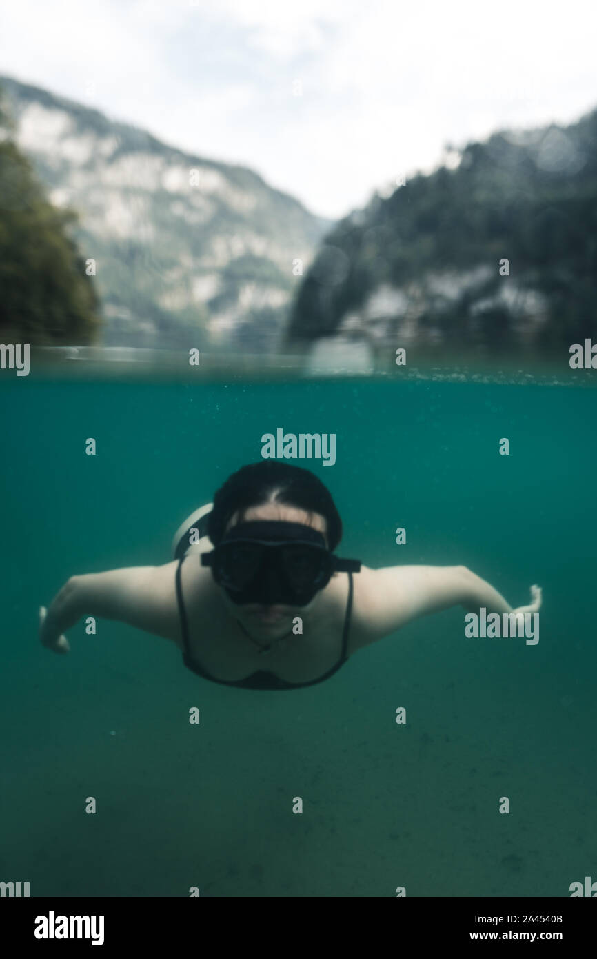 Half half picture of girl swimming in a lake with a mask, in the background are the alps at the Koenigssee (Königssee) in the Berchtesgadener Land, Ba Stock Photo