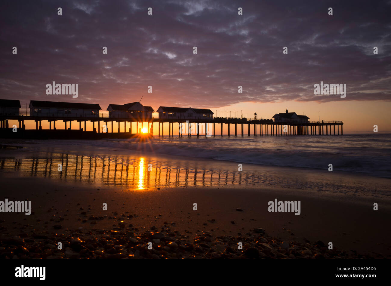 Southwold pier at sunrise, taken from the deserted beach from a low viewpoint with pebbles in the foreground. Stock Photo