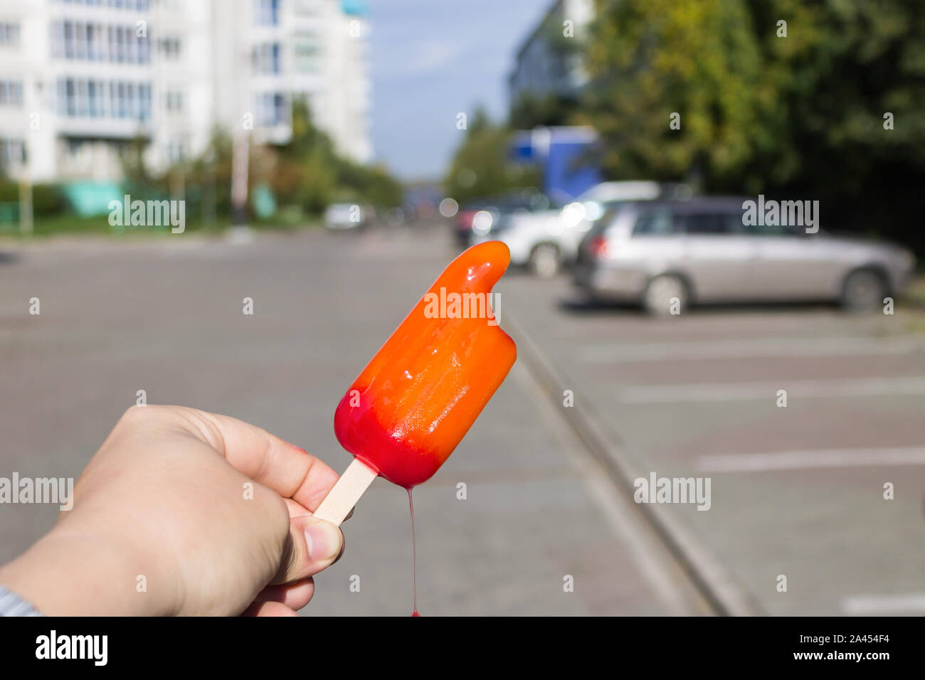 Ice cream melts in hands on the street against the background of machines Stock Photo