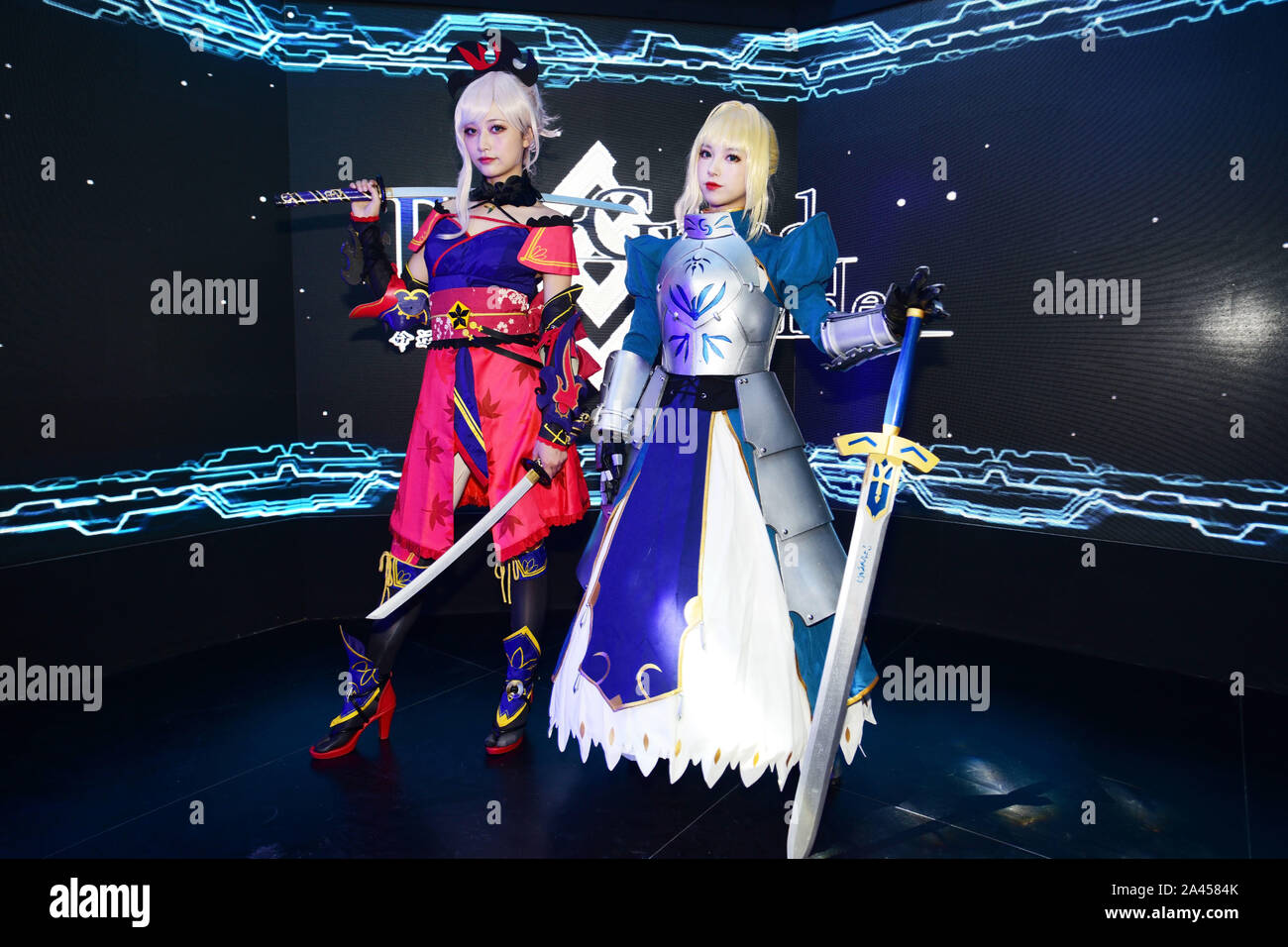 Chinese showgirls dressed in cosplay costumes featuring Miyamoto Musashi and Saber, whose real name is Artoria Pendragon, from 'Fate/Grand Order' pose Stock Photo